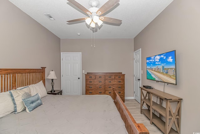 bedroom featuring a textured ceiling, visible vents, and a ceiling fan