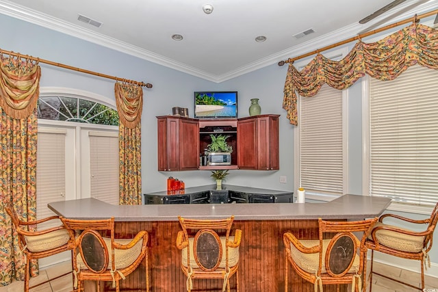 kitchen featuring ornamental molding, visible vents, stainless steel microwave, and a breakfast bar area