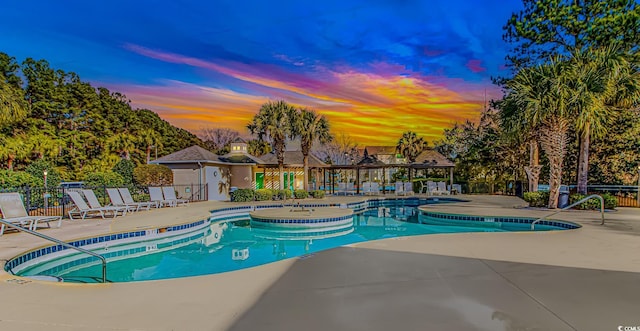 pool at dusk with a patio area, a community pool, and fence