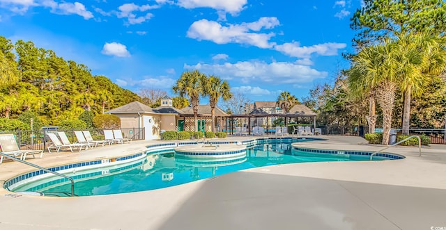 community pool with a patio area and fence