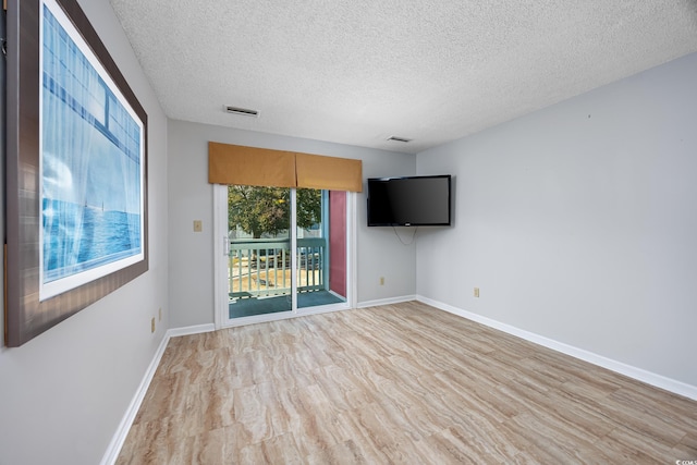 empty room with a textured ceiling and light wood-type flooring