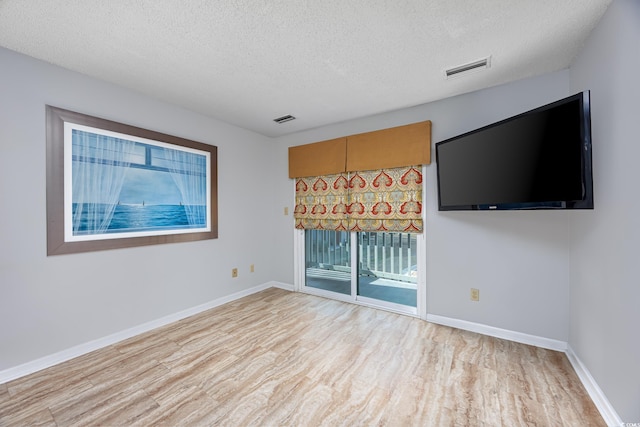 empty room with a textured ceiling and light wood-type flooring