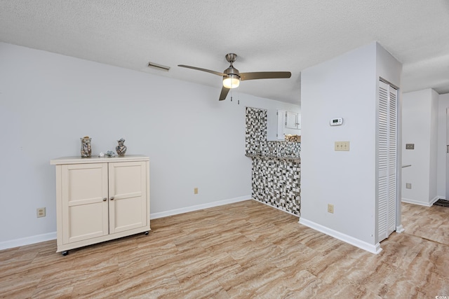 unfurnished room featuring ceiling fan, light hardwood / wood-style floors, and a textured ceiling