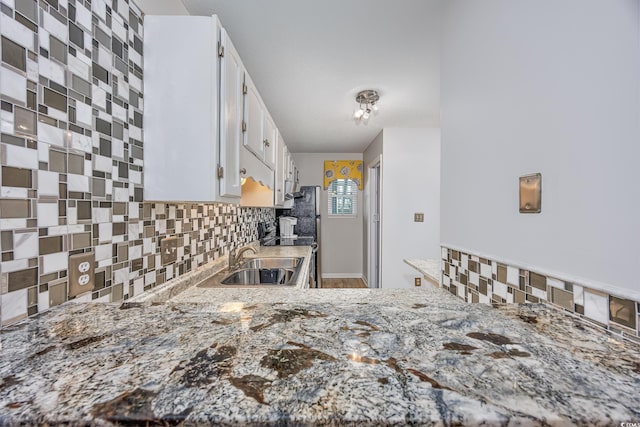 kitchen with white cabinetry, light stone countertops, sink, and decorative backsplash