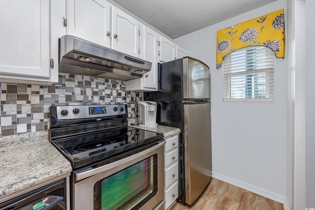 kitchen with appliances with stainless steel finishes, white cabinetry, decorative backsplash, light stone countertops, and a textured ceiling