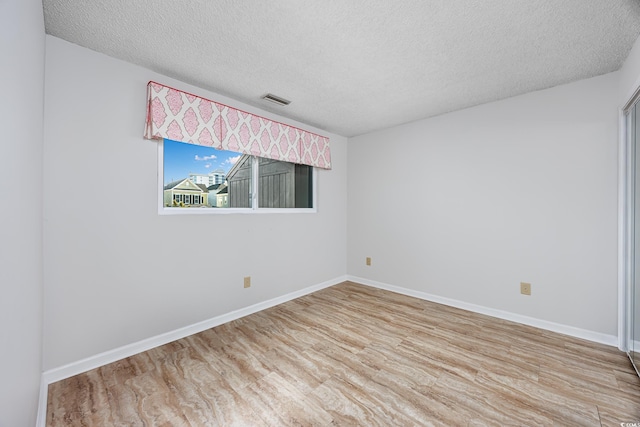 unfurnished room with wood-type flooring and a textured ceiling