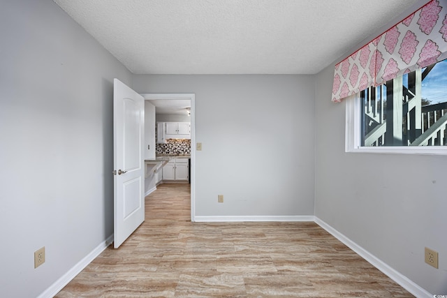 unfurnished room with a textured ceiling and light wood-type flooring