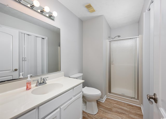 bathroom with hardwood / wood-style flooring, vanity, an enclosed shower, and toilet