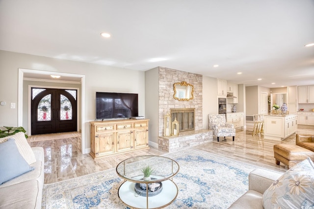 living room featuring a stone fireplace, light hardwood / wood-style flooring, and french doors