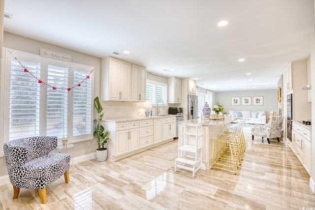 kitchen with sink, a breakfast bar, appliances with stainless steel finishes, a center island, and light stone countertops