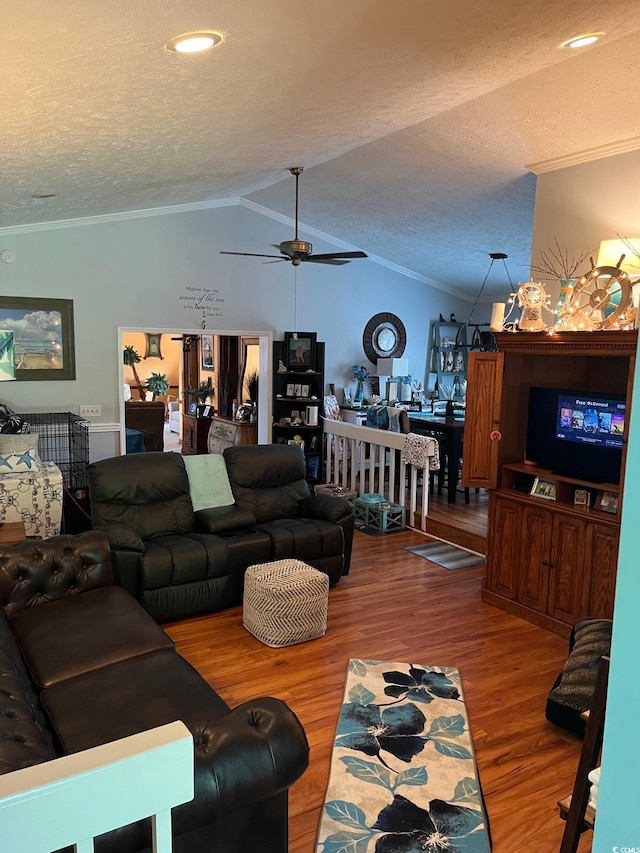 living room featuring lofted ceiling, hardwood / wood-style flooring, ceiling fan, ornamental molding, and a textured ceiling