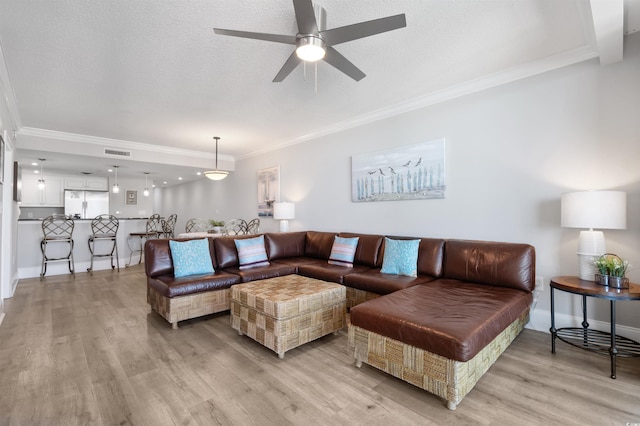 living room featuring ornamental molding, ceiling fan, a textured ceiling, and light hardwood / wood-style floors