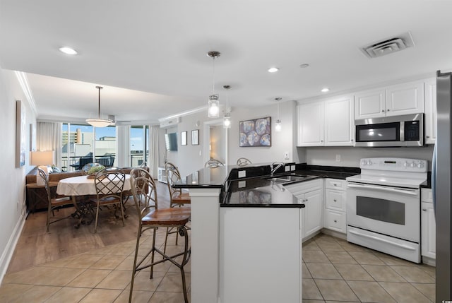 kitchen featuring appliances with stainless steel finishes, pendant lighting, white cabinetry, a breakfast bar area, and kitchen peninsula