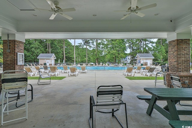 view of patio with ceiling fan, a community pool, and a shed