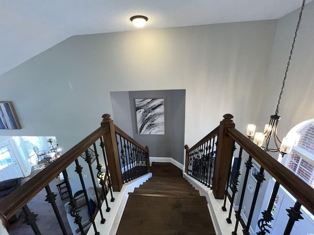 staircase featuring lofted ceiling and a chandelier