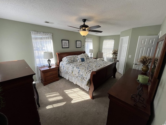 bedroom with multiple windows, carpet flooring, a textured ceiling, and ceiling fan