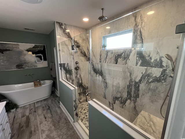 bathroom with wood-type flooring and shower with separate bathtub