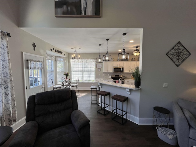 living room featuring dark hardwood / wood-style flooring and ceiling fan with notable chandelier