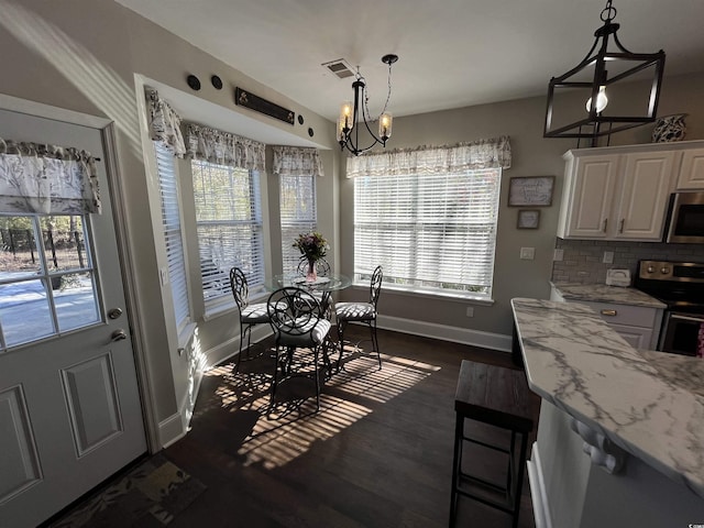 dining room featuring a notable chandelier, dark hardwood / wood-style floors, and a healthy amount of sunlight