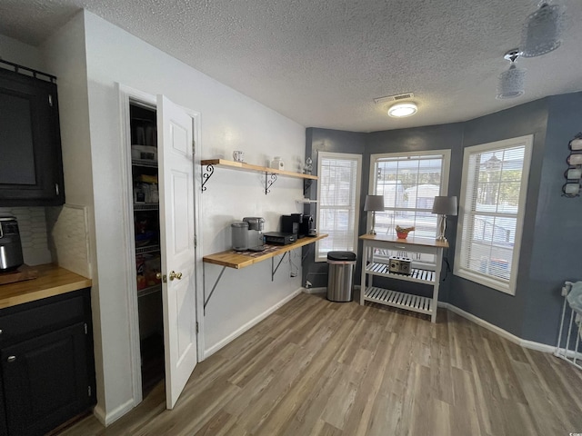 kitchen with a textured ceiling, wood counters, and light hardwood / wood-style flooring