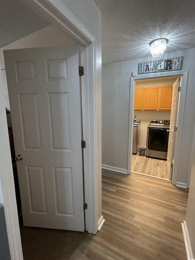 hallway featuring independent washer and dryer, a textured ceiling, and light wood-type flooring