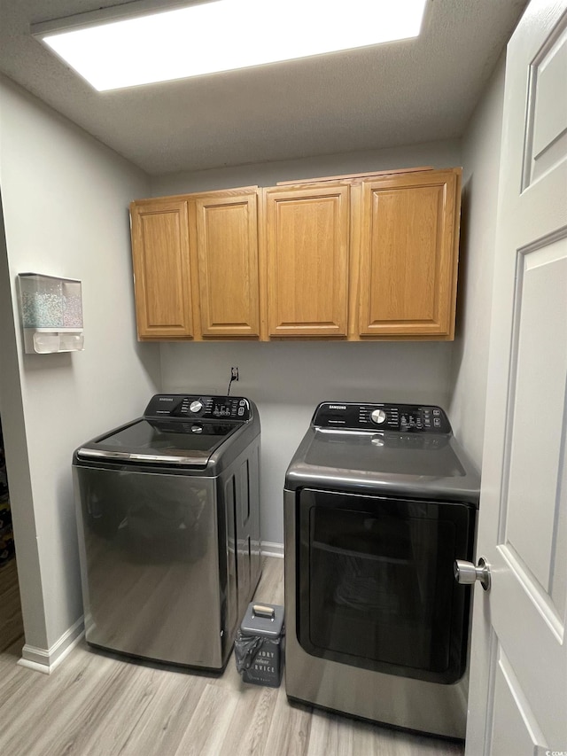 laundry room with separate washer and dryer, light hardwood / wood-style floors, and cabinets