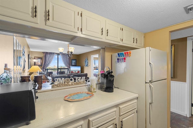 kitchen with a notable chandelier, white fridge, and a textured ceiling