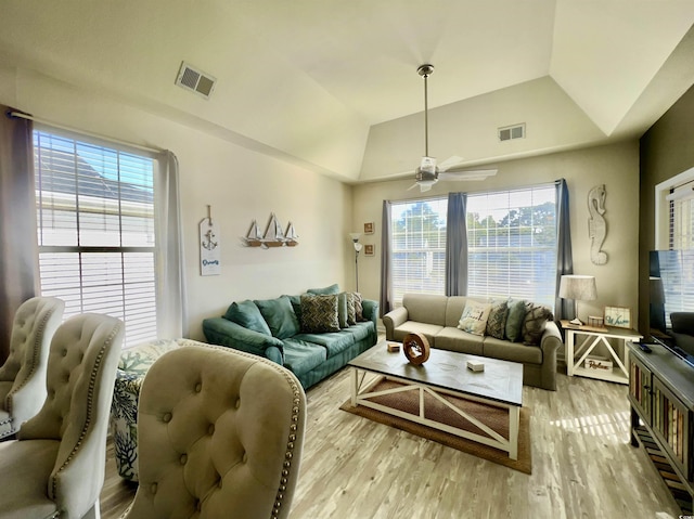 living room featuring vaulted ceiling, ceiling fan, light hardwood / wood-style floors, and a tray ceiling