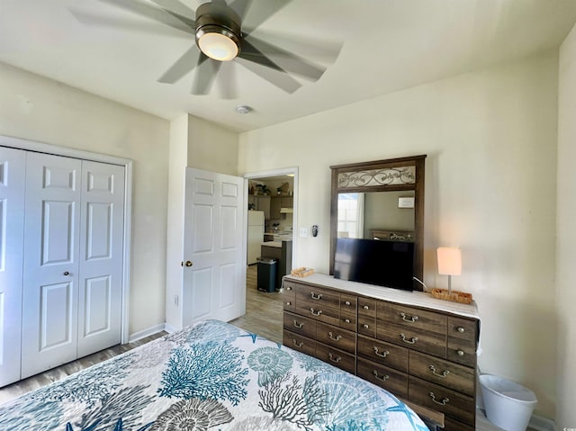 bedroom featuring light hardwood / wood-style flooring, a closet, ceiling fan, and white refrigerator