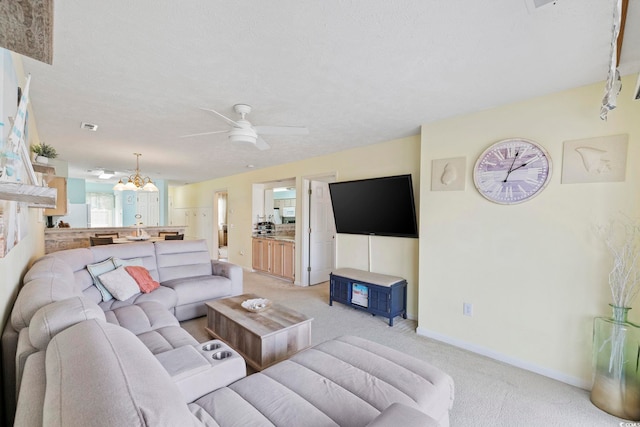 carpeted living room with ceiling fan with notable chandelier and a textured ceiling