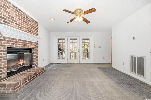 unfurnished living room featuring ceiling fan, carpet flooring, a fireplace, and french doors