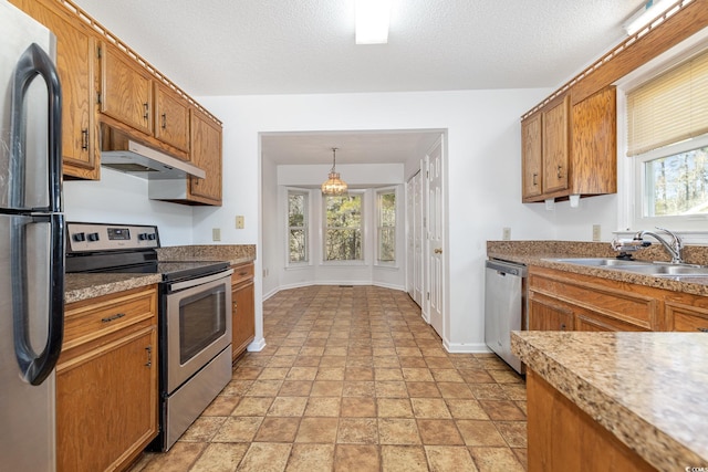 kitchen featuring stainless steel appliances, sink, pendant lighting, and a textured ceiling