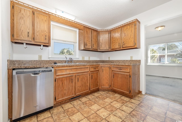 kitchen featuring sink, stainless steel dishwasher, light colored carpet, and a textured ceiling