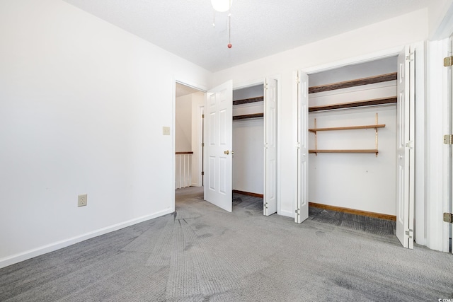 unfurnished bedroom featuring carpet flooring, a textured ceiling, and two closets