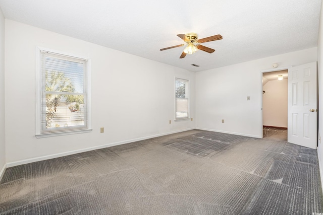 unfurnished room featuring ceiling fan, dark carpet, and a textured ceiling