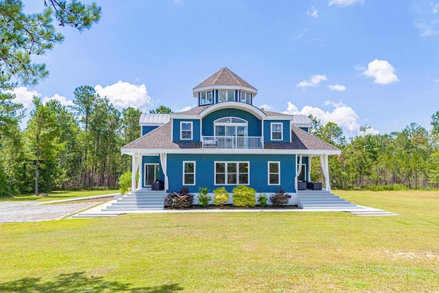 view of front facade featuring a front lawn, roof with shingles, and a balcony