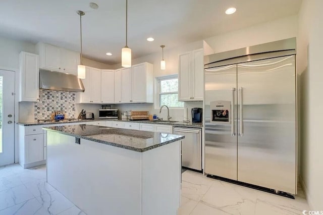 kitchen featuring marble finish floor, stainless steel appliances, white cabinets, and under cabinet range hood