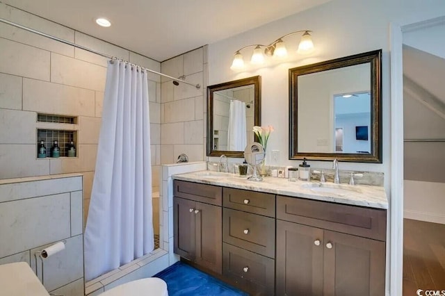 bathroom featuring toilet, double vanity, a sink, and shower / bath combo with shower curtain