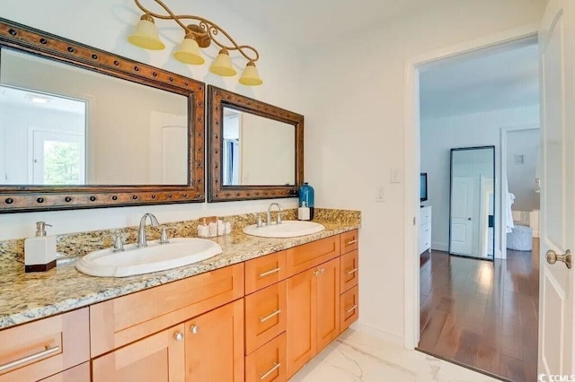 bathroom featuring marble finish floor, double vanity, a sink, and baseboards