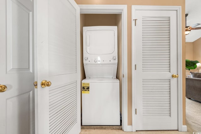 laundry room with ceiling fan, stacked washer / drying machine, and light carpet