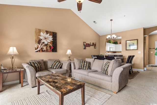 carpeted living room with ceiling fan with notable chandelier and high vaulted ceiling