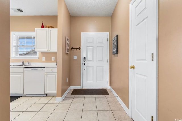 doorway to outside with sink, a textured ceiling, and light tile patterned flooring