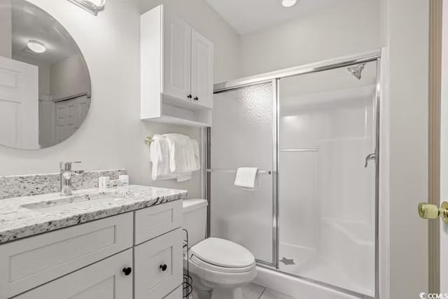 bathroom with vanity, a shower with shower door, and toilet