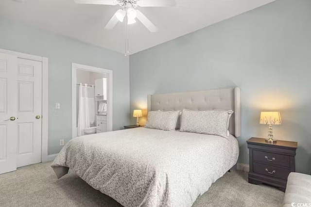 bedroom featuring ceiling fan, light colored carpet, and ensuite bath