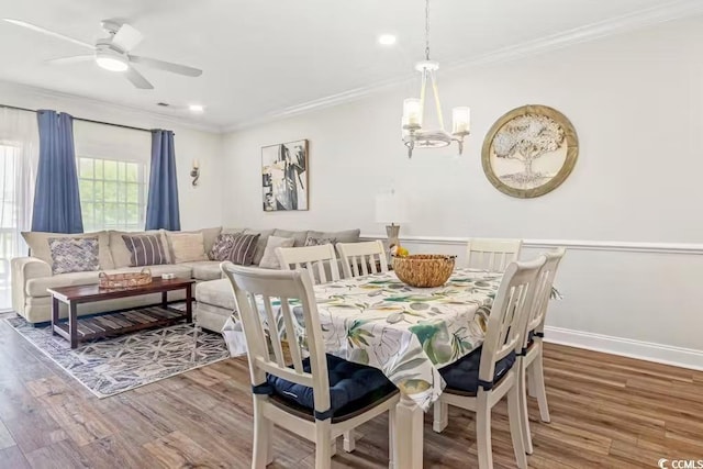 dining space with ornamental molding, ceiling fan with notable chandelier, and wood-type flooring