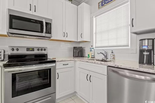 kitchen featuring sink, white cabinetry, light stone counters, appliances with stainless steel finishes, and backsplash