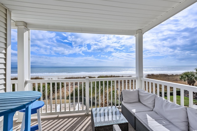 balcony with an outdoor living space, a beach view, and a water view