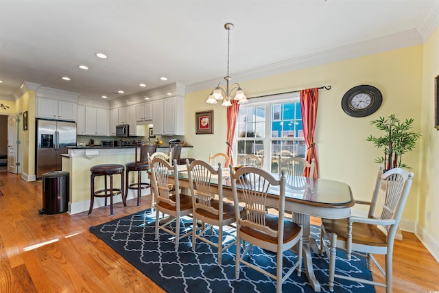 dining room with crown molding, an inviting chandelier, and light hardwood / wood-style floors