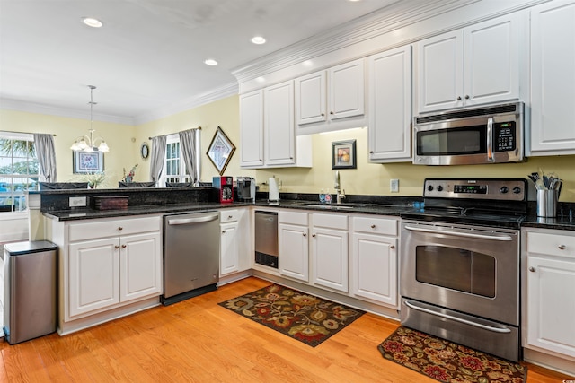 kitchen featuring sink, appliances with stainless steel finishes, white cabinetry, ornamental molding, and kitchen peninsula