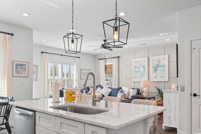 kitchen with sink, white cabinetry, decorative light fixtures, dishwasher, and a kitchen island with sink